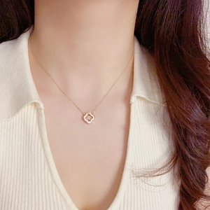 Collier trèfle doré élégant avec pendentif en nacre et pierre porté par un mannequin