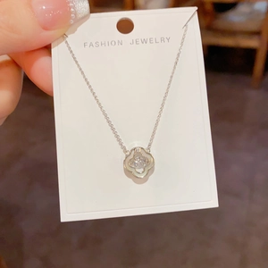Détail du pendentif trèfle argenté avec nacre et zircon central sur carte de support