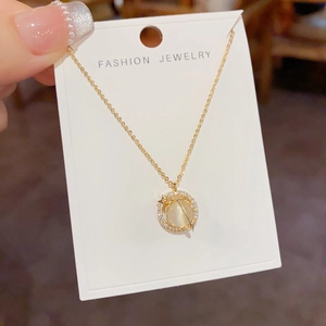 Detail of gold rotating cat-eye stone necklace with crystal stars and orbital design
