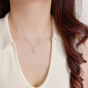 Close-up of a gold necklace featuring a rotating cat-eye stone pendant with pavé crystals