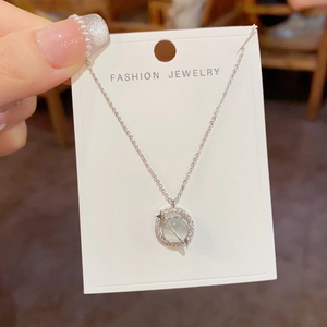Close-up of silver planetary opal pendant necklace with sparkling pavé crystals on a card