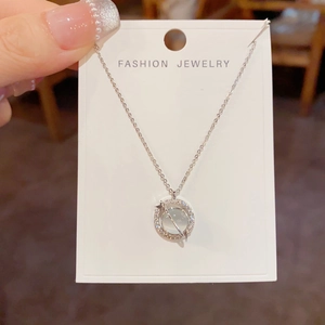 Close-up of silver planet pendant necklace featuring a cat eye stone and cubic zirconia