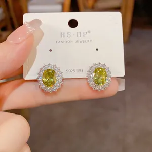 Détail de boucles d'oreilles ovales en gemme jaune avec halo et tiges en argent S925