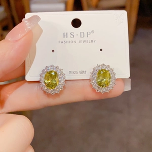 Détail de boucles d'oreilles en argent S925 avec pierre jaune ovale et diamants