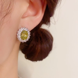 Gros plan de boucles d'oreilles en zircon vert olive portées par un mannequin réel