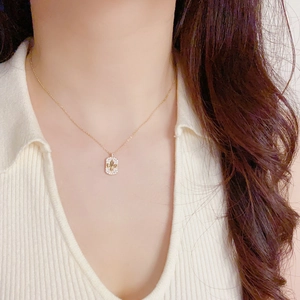 Gros plan du collier pendentif fleur de lys doré avec cristaux pavés sur un mannequin