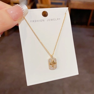 Détail du collier à pendentif rectangle doré avec pavé de cristaux et fleur de lys