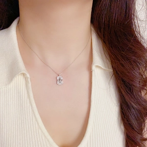 Gros plan d'un collier avec pendentif fleur de lys argenté serti de cristaux brillants