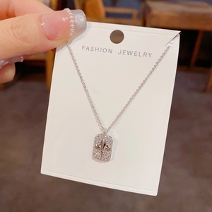 Vue détaillée d'un collier pendentif carré avec fleur de lys et pierres de zircon brillantes
