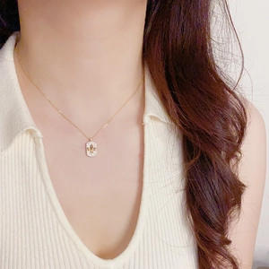 Détail du collier rectangle doré avec pendentif fleur de lys et pavé de cristaux