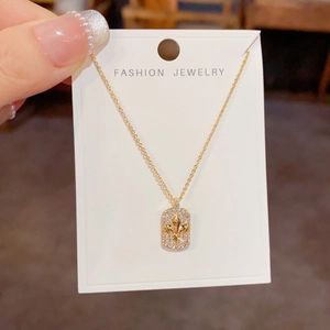 Élégant collier carré doré fleur de lys avec cristaux étincelants sur sa carte