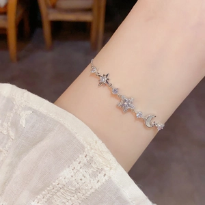 Detailed close-up of a silver star and moon bracelet with zircon pavé on a wrist
