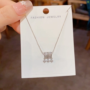 Detail van een fonkelende ketting met cilinderhanger en kwastjes in de hand gehouden