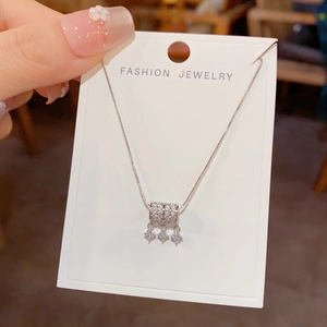 Detail van zilveren halsketting met glanzende cilinder hanger en kleine ster hangertjes