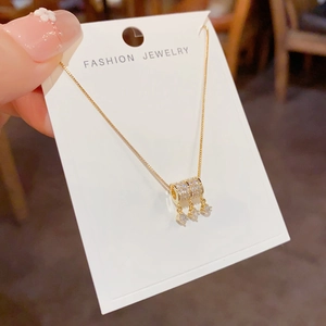 Detail van de goudkleurige ketting met zirkoon cilinder hanger en drie kwastjes