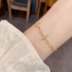 Close-up of a delicate gold-plated cross bracelet with crystals on a woman's wrist