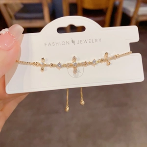 Adjustable gold cross bracelet with sparkling cubic zirconia on a slider chain