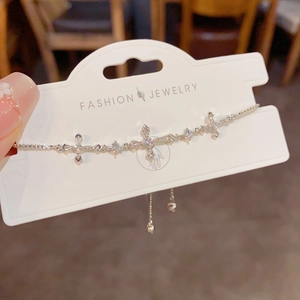 Detailed view of a silver-toned cross bracelet with sparkling crystals on display card.