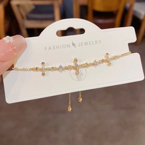 Close-up of golden cross charm bracelet with sparkling rhinestones and adjustable chain