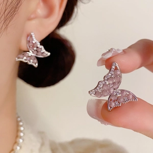 Detalle de pendientes de mariposa en plata s925 con cristales rosas en el lóbulo de oreja