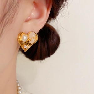 Boucles d'oreilles cœur dorées vintage avec perle et opale rose portées par un mannequin