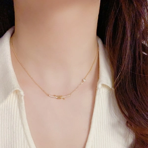 Elegant gold-plated knot smile necklace with shimmering diamonds on a white knit sweater