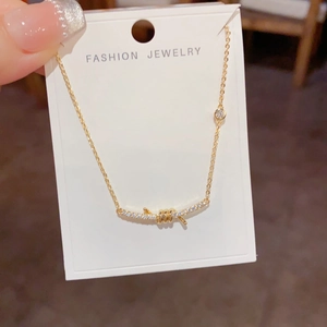 Macro detail of gold knot necklace featuring shimmering pavé diamonds on a curved bar