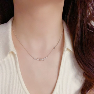 Sparkling knot smile necklace in silver finish worn on neck over white ribbed sweater