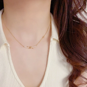 Close-up of a gold knot smile necklace with zircon inlay worn by a female model