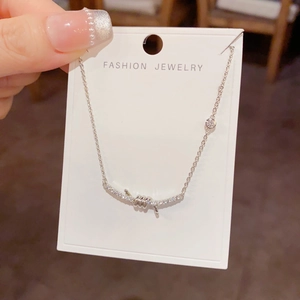 Detail of silver knot necklace with sparkling zircon pendant held against a jewelry card