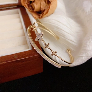 Elegant gold double-layer open bangle featuring sparkling pavé crystals and clover charms
