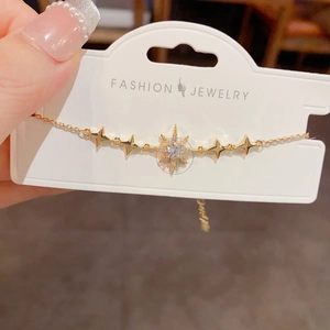 Détail d'un bracelet doré avec breloques d'étoiles et zircons brillants sur support