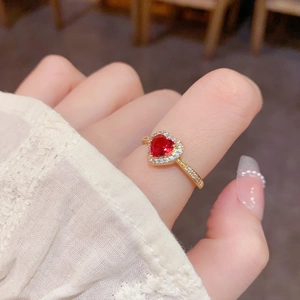 Gros plan d'une bague avec pierre précieuse rouge en cœur et micro-pavé de cristaux