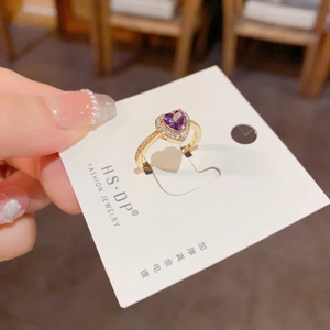 Gros plan sur une bague cœur avec gemme violette, placage or et cristaux scintillants