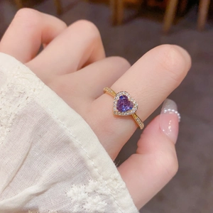 Détail macro d'une bague avec pierre précieuse violette en cœur et monture dorée sertie