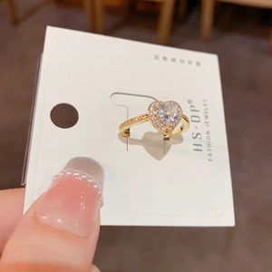 Détail d'une bague cœur plaquée or avec zircons brillants sur une carte de présentation