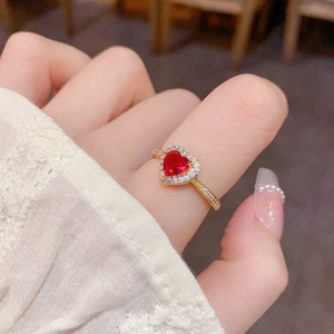 Bague coeur en or avec rubis rouge et diamants portée sur un doigt élégant