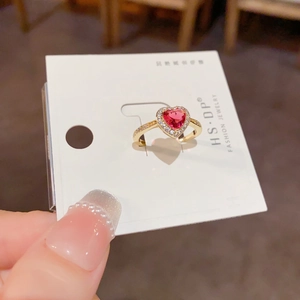 Détail d'une bague cœur dorée avec zircon rouge et sertissage micro-pavé délicat