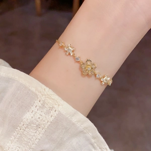 Elegant gold adjustable bracelet featuring sparkling petal charms and white cubic zirconia