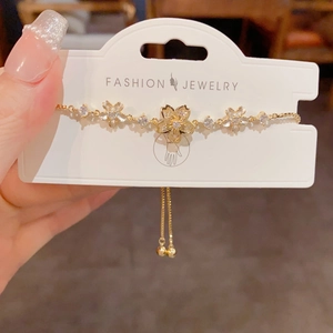 Close-up of a gold cherry blossom adjustable bracelet with sparkling zircon accents