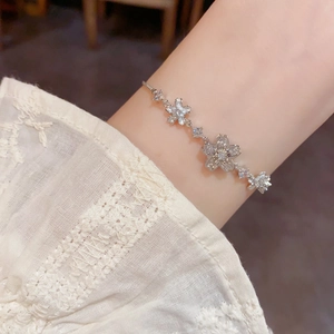 Detail of flower charm bracelet with sparkling crystals on a lace sleeve background