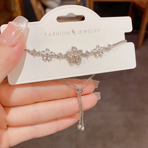Detail of silver cherry blossom bolo bracelet with sparkling crystals on display card