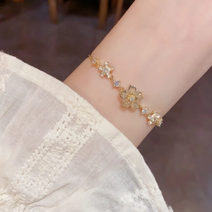 Detailed close-up of golden floral bracelet with sparkling zircon petals on a wrist