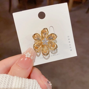 Détail macro d'une broche pétale dorée avec cristaux ambrés et petits diamants fins