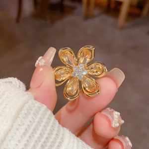 Détail macro d'une broche fleur vintage en cristal ambré avec des pétales dorés brillants