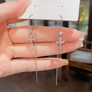 Gros plan de boucles d'oreilles traversantes en argent avec croix sertie de zircons fins