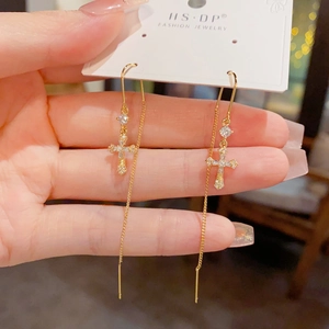 Boucles d'oreilles pendantes croix dorées avec zircone sur carte de présentation