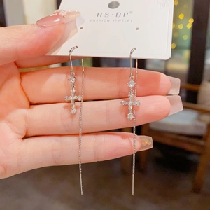 Gros plan de boucles d'oreilles traversantes croix en argent avec zircone