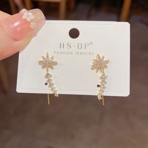 Close-up of gold starburst earrings with sparkling white crystals and curved diamond design
