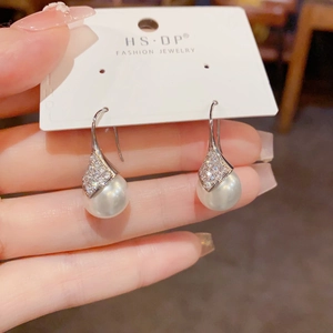 Detalle de pendientes de perlas romboidales con circonitas y ganchos de plata